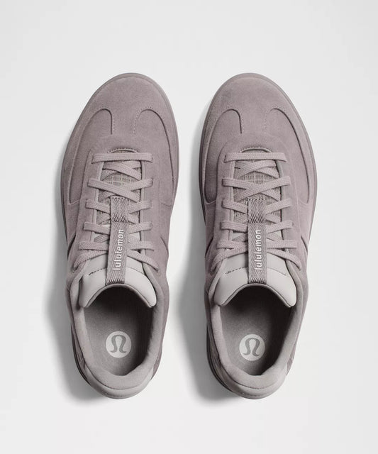 Pair of gray sneakers with a visible brand logo on a light gray background