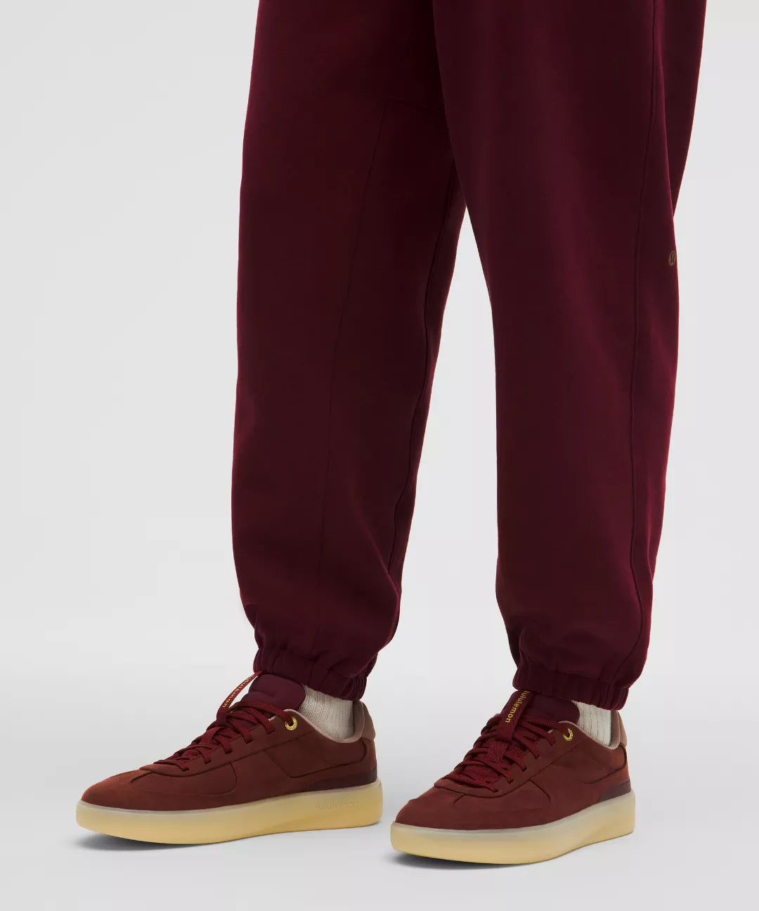 Maroon jogger pants and matching sneakers on a white background