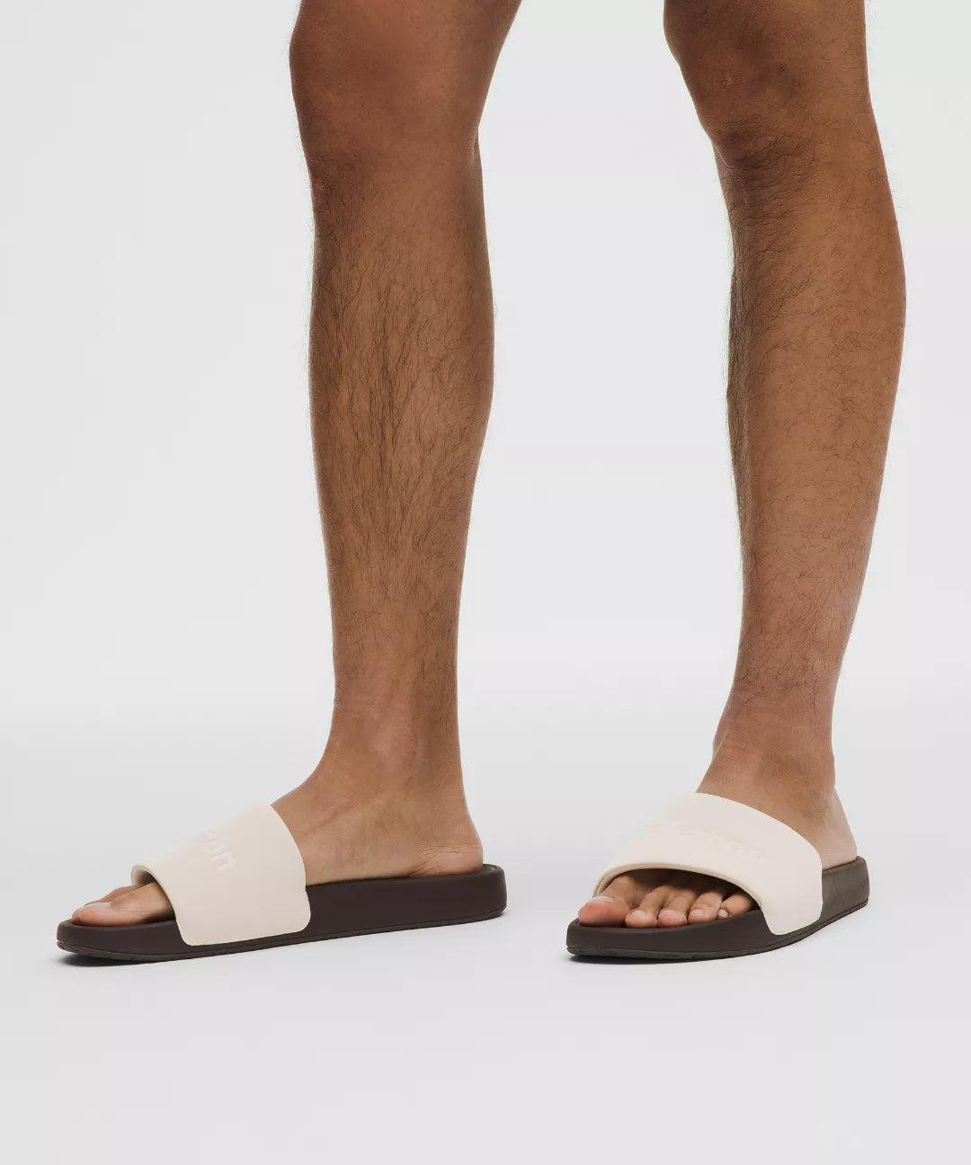 White sandals with black soles worn by a person on a white background