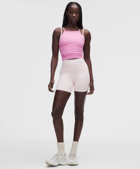 Person wearing a pink tank top and light pink shorts on a white background