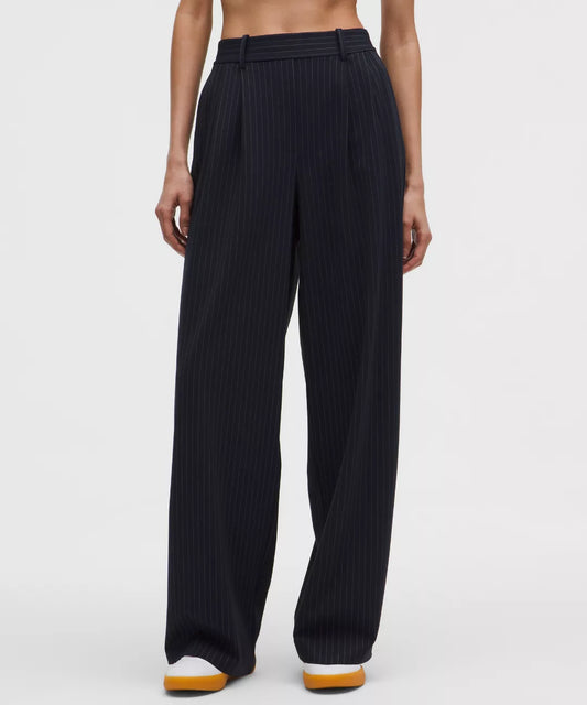 Black pinstripe pants worn by a person on a white background