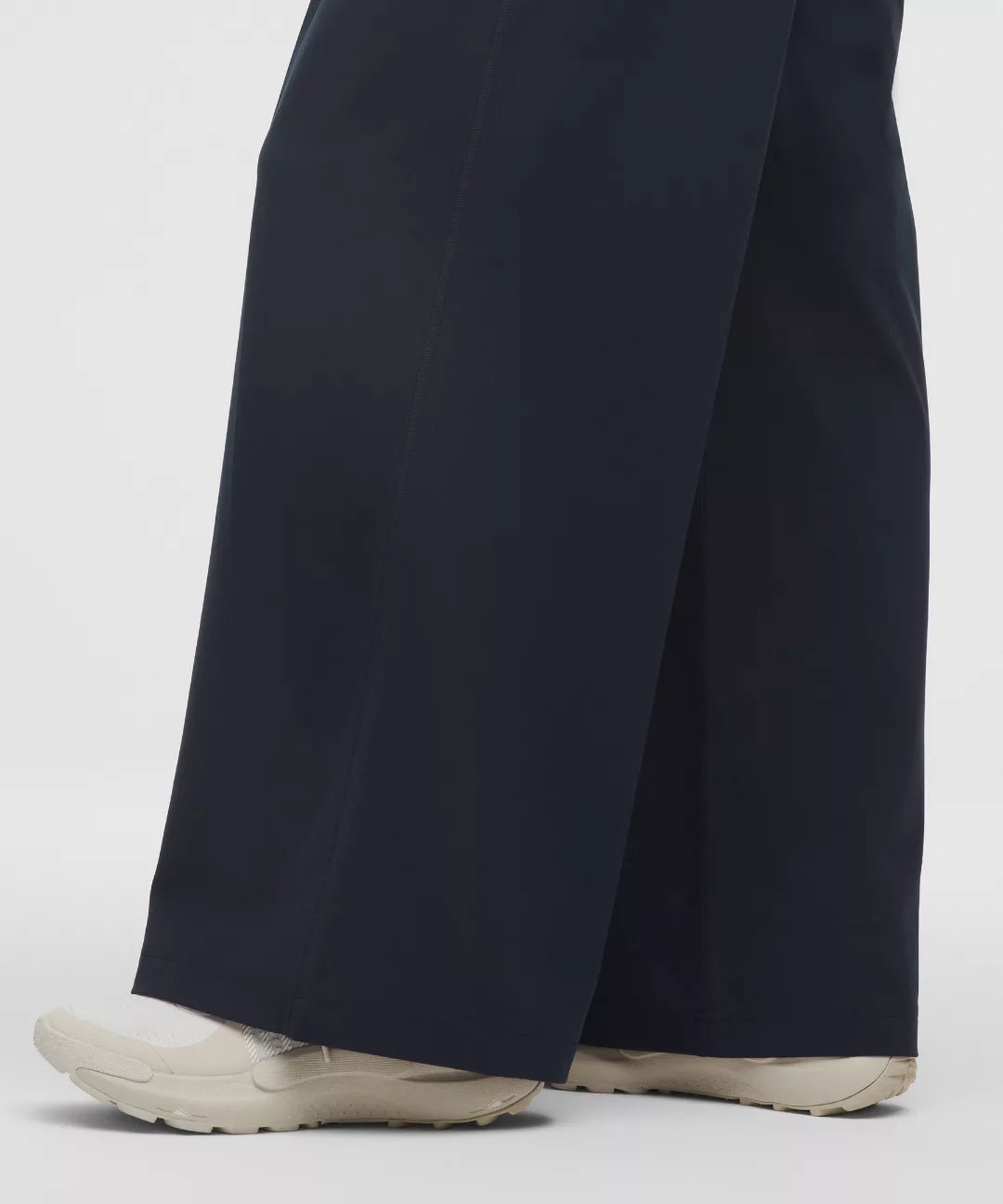 Dark blue pants worn by a person on a light gray background