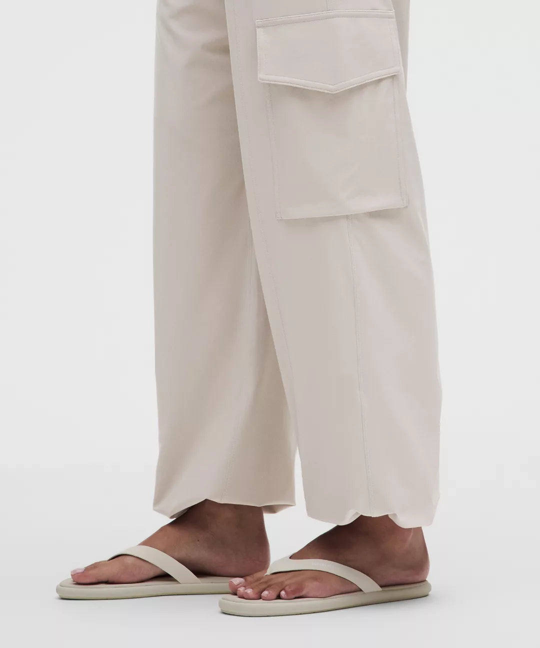 Person wearing beige sandals and light-colored pants on a white background