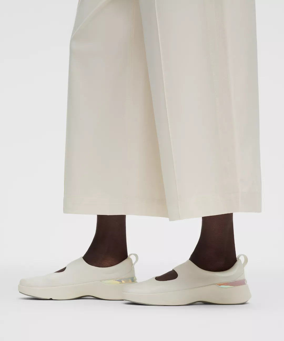 White sneakers worn with white pants on a light gray background