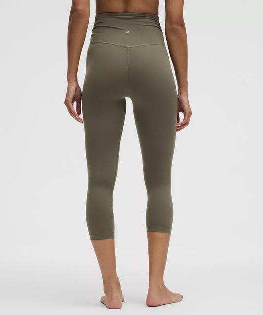 Person wearing olive green leggings on a white background