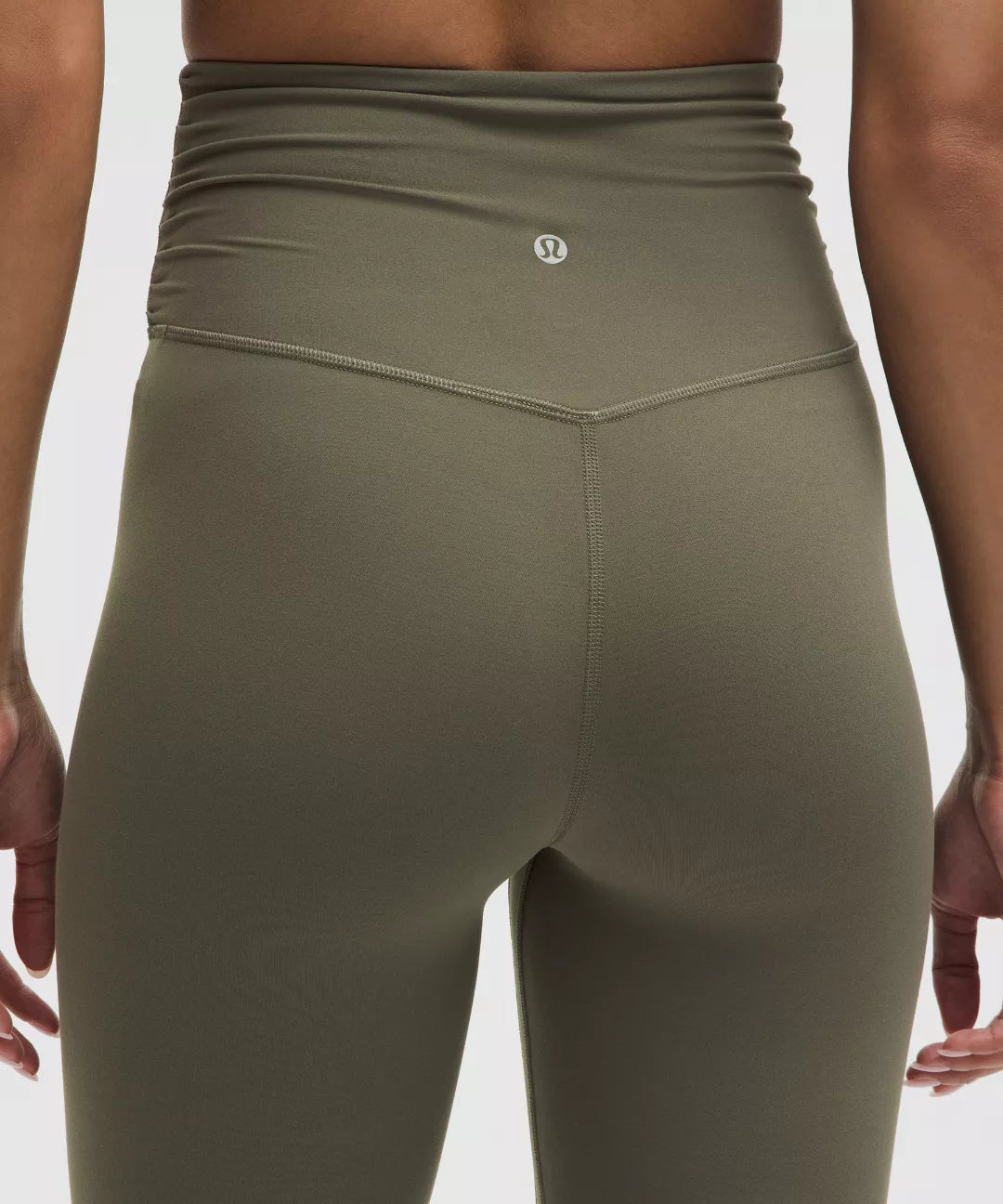 Olive green leggings worn by a person on a light gray background