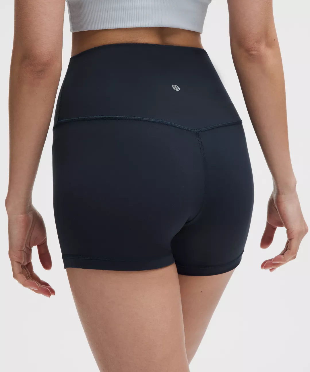 Person wearing black athletic shorts on a plain background