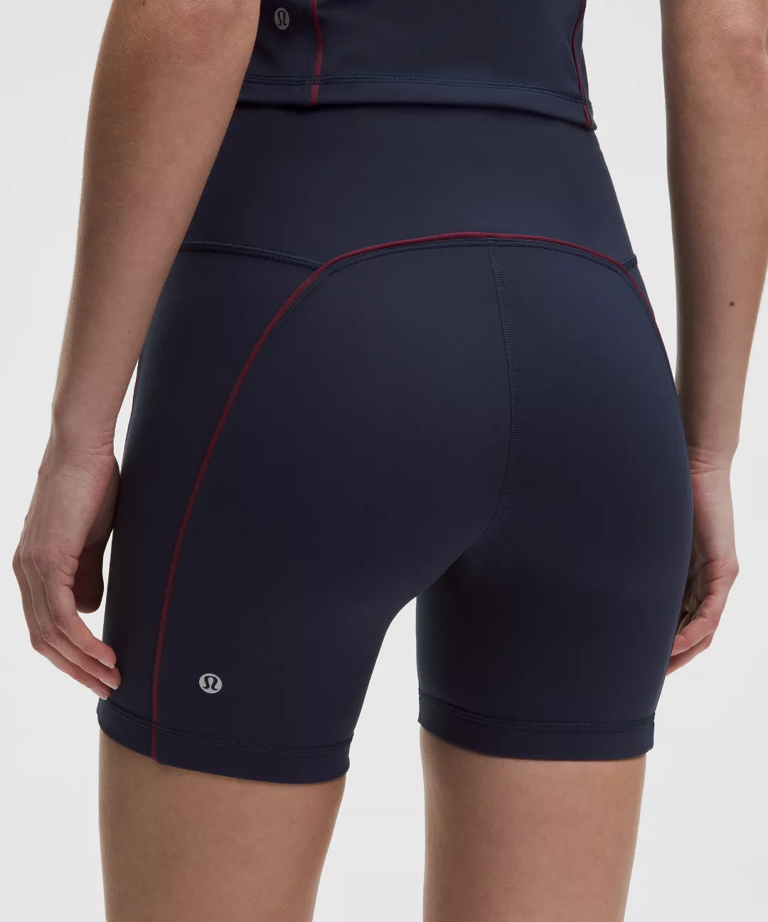 Navy blue athletic shorts with red stitching on a white background