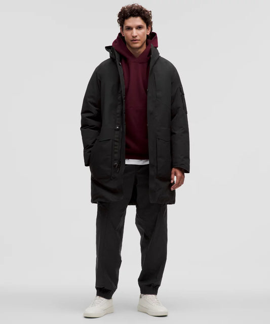 Man wearing a black coat over a red hoodie on a white background