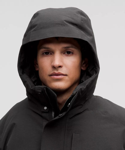 Person wearing a black hooded jacket against a gray background