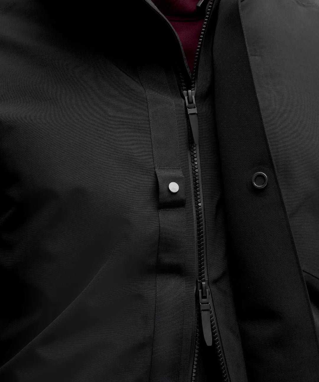 Close-up of a black jacket with a zipper and buttons.