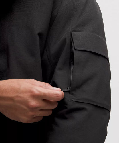 Person wearing a black jacket with a pocket on a light gray background