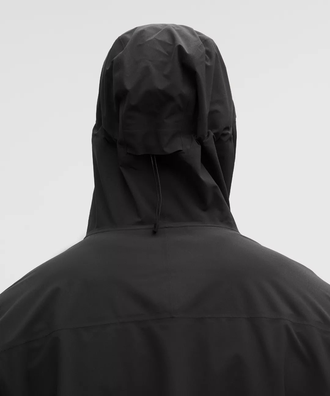 Person wearing a black hooded jacket on a light gray background