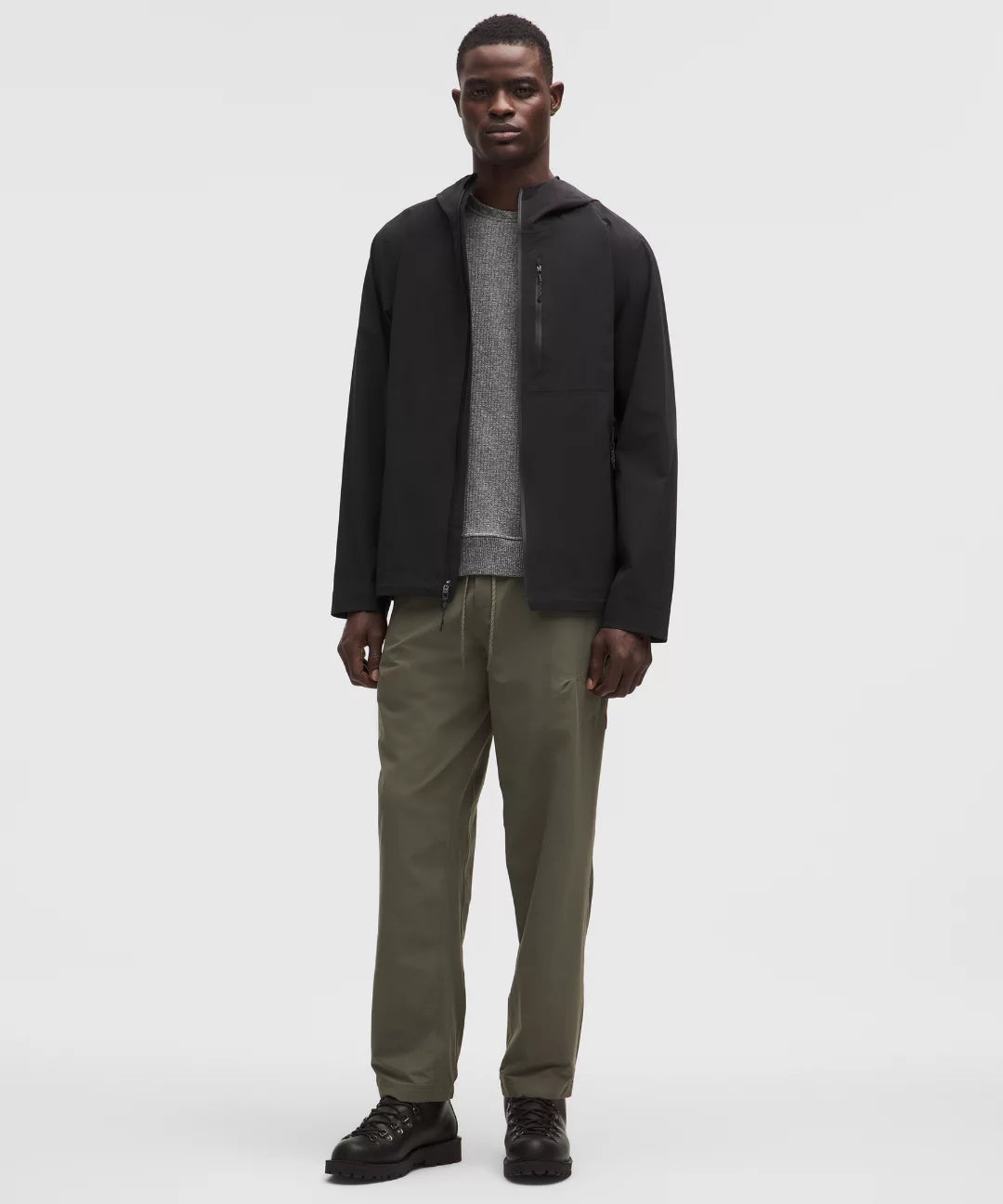 Man wearing a black jacket and green pants on a white background