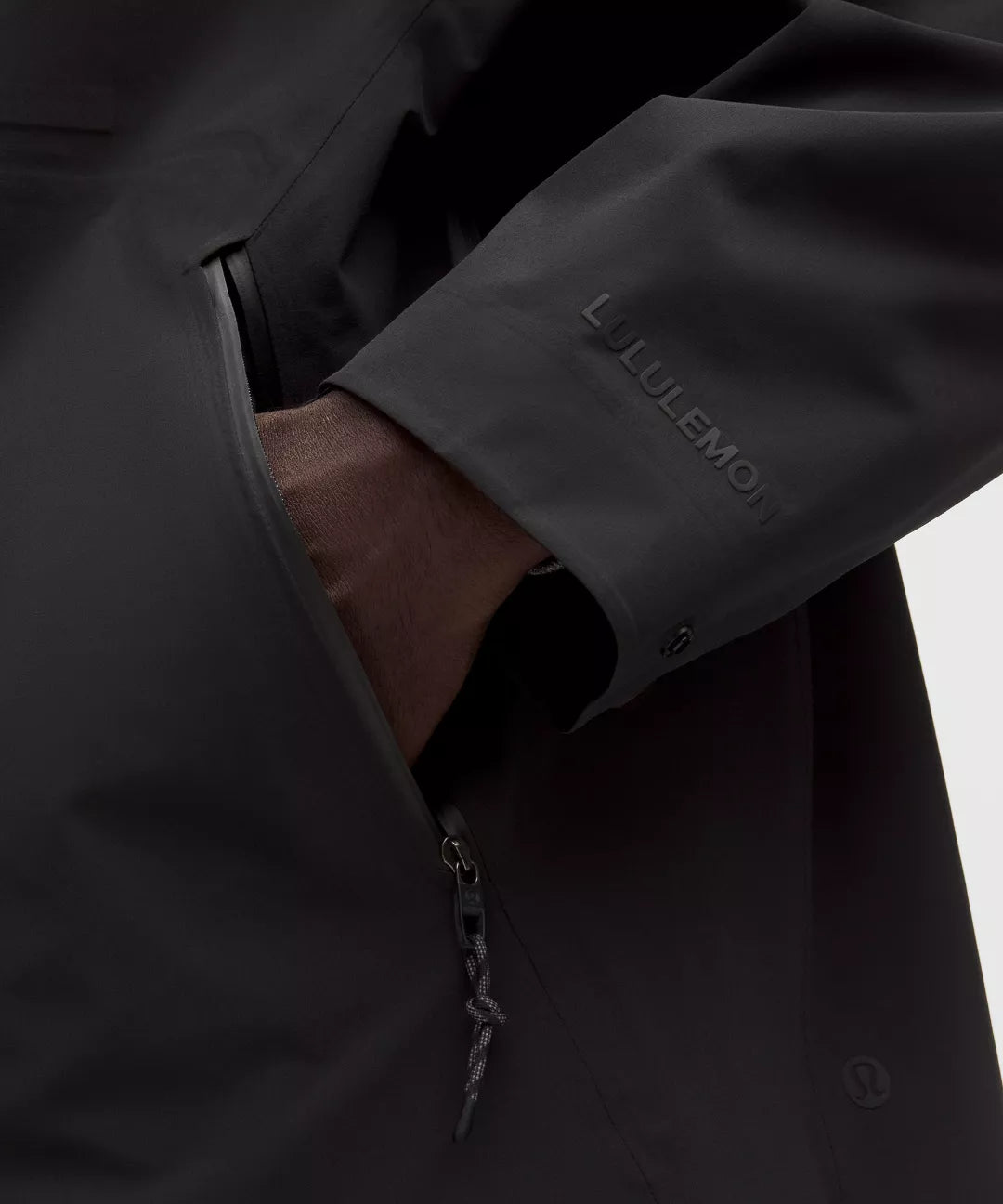 Close-up of a dark jacket with a visible brand logo on a light background