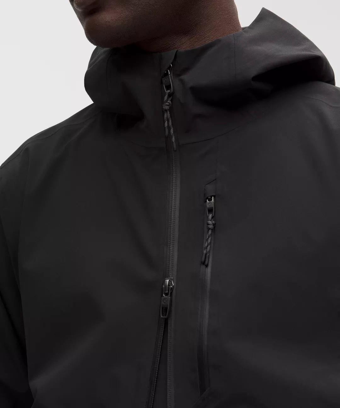Close-up of a black jacket with a hood and zipper on a neutral background