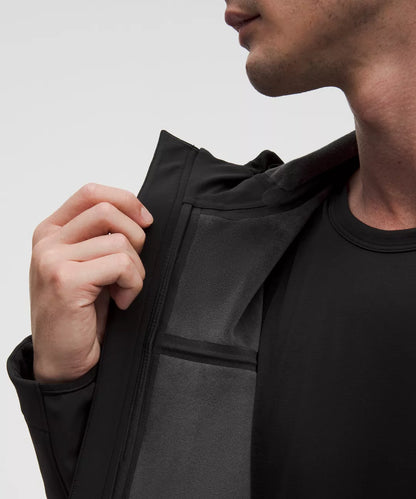 Person wearing a black jacket with a plain background