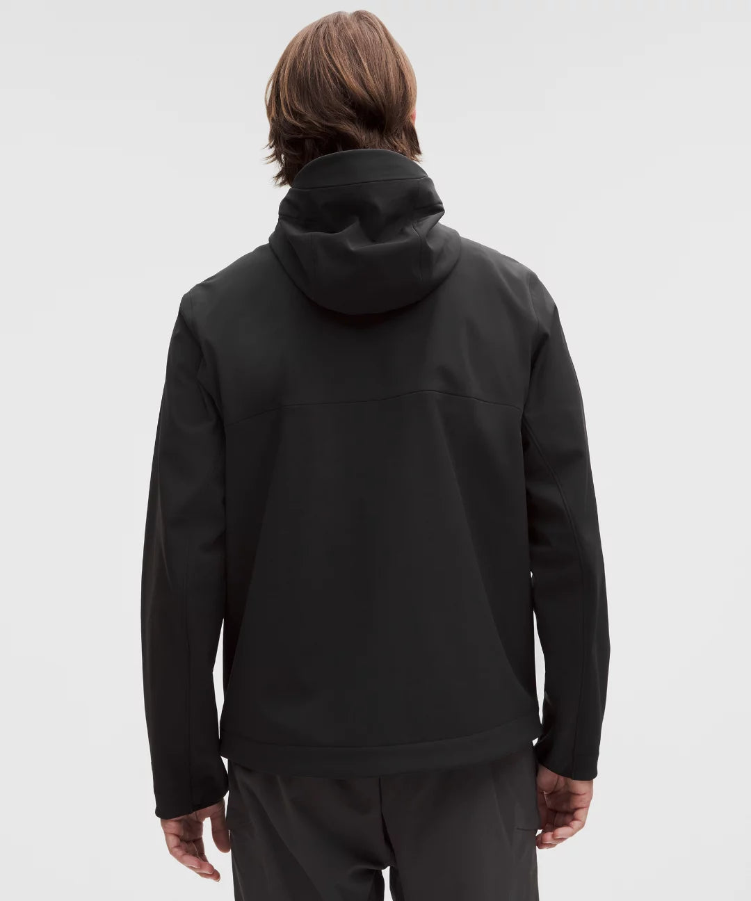 Person wearing a black hoodie and pants on a light gray background