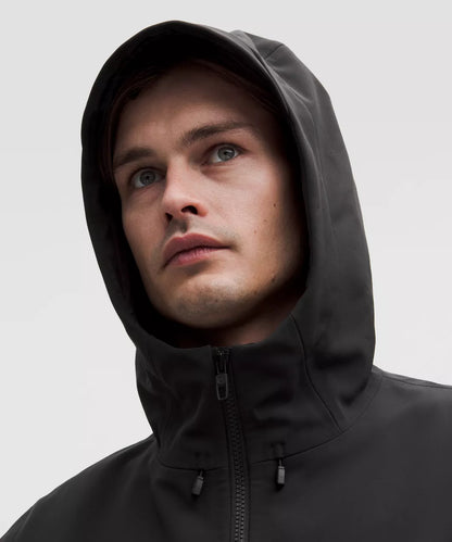 Person wearing a black hooded jacket against a light gray background