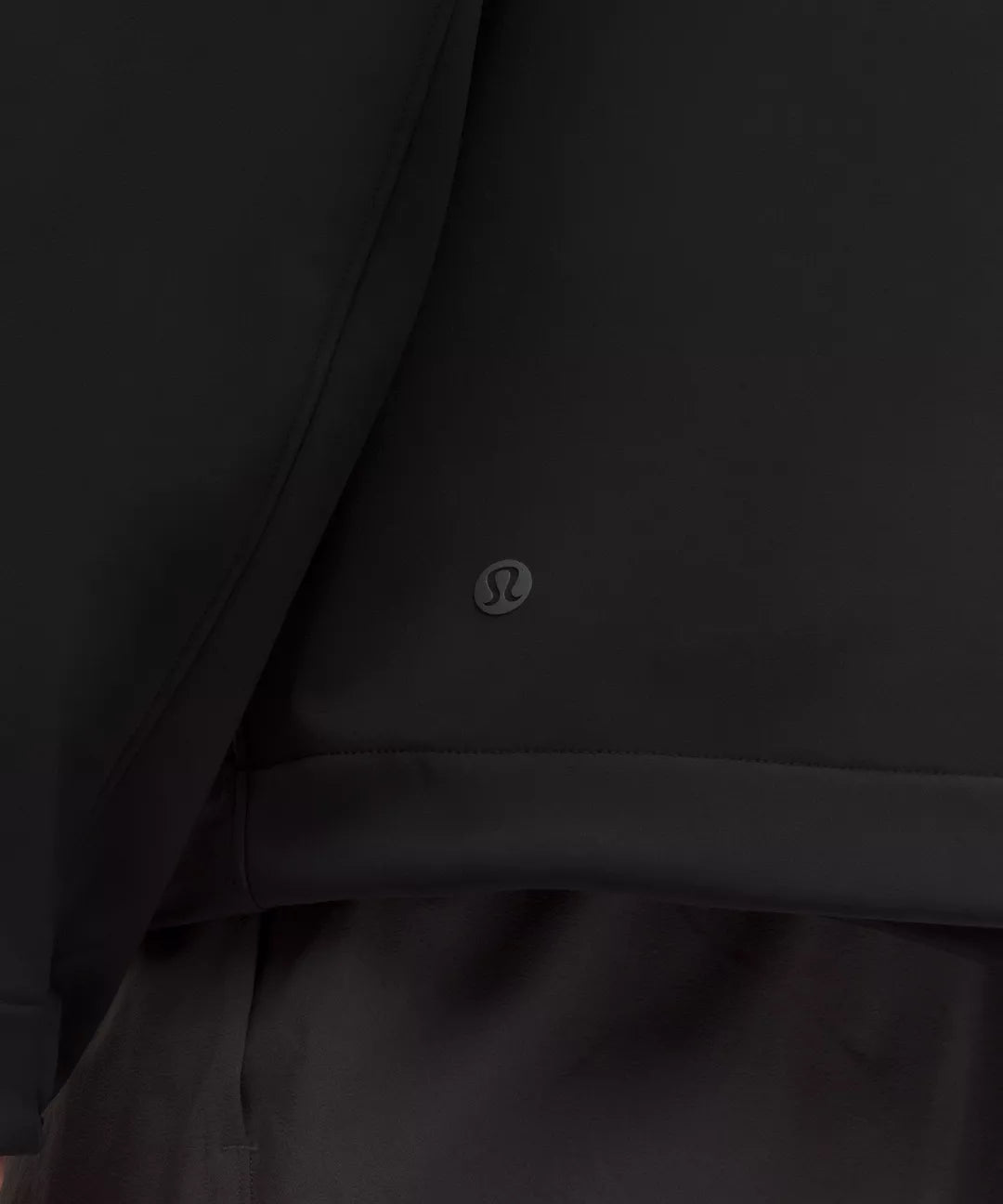 Close-up of a black jacket with a visible brand logo on a dark background