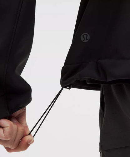 Close-up of a person adjusting the drawstring of a black jacket on a light gray background