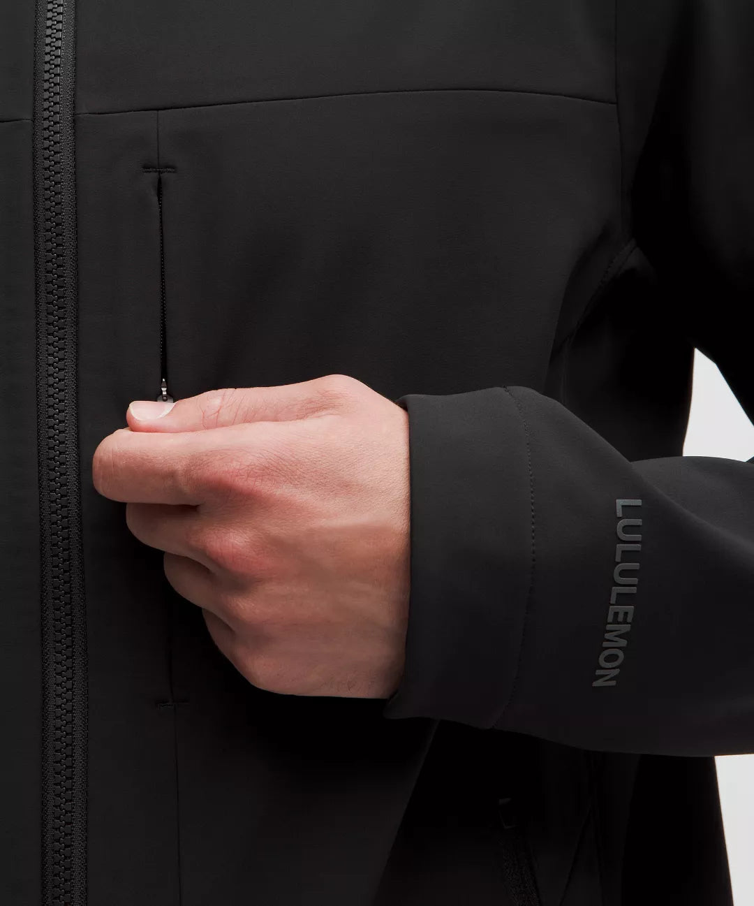 Close-up of a person wearing a black jacket with 'Lululemon' branding, focusing on the sleeve.