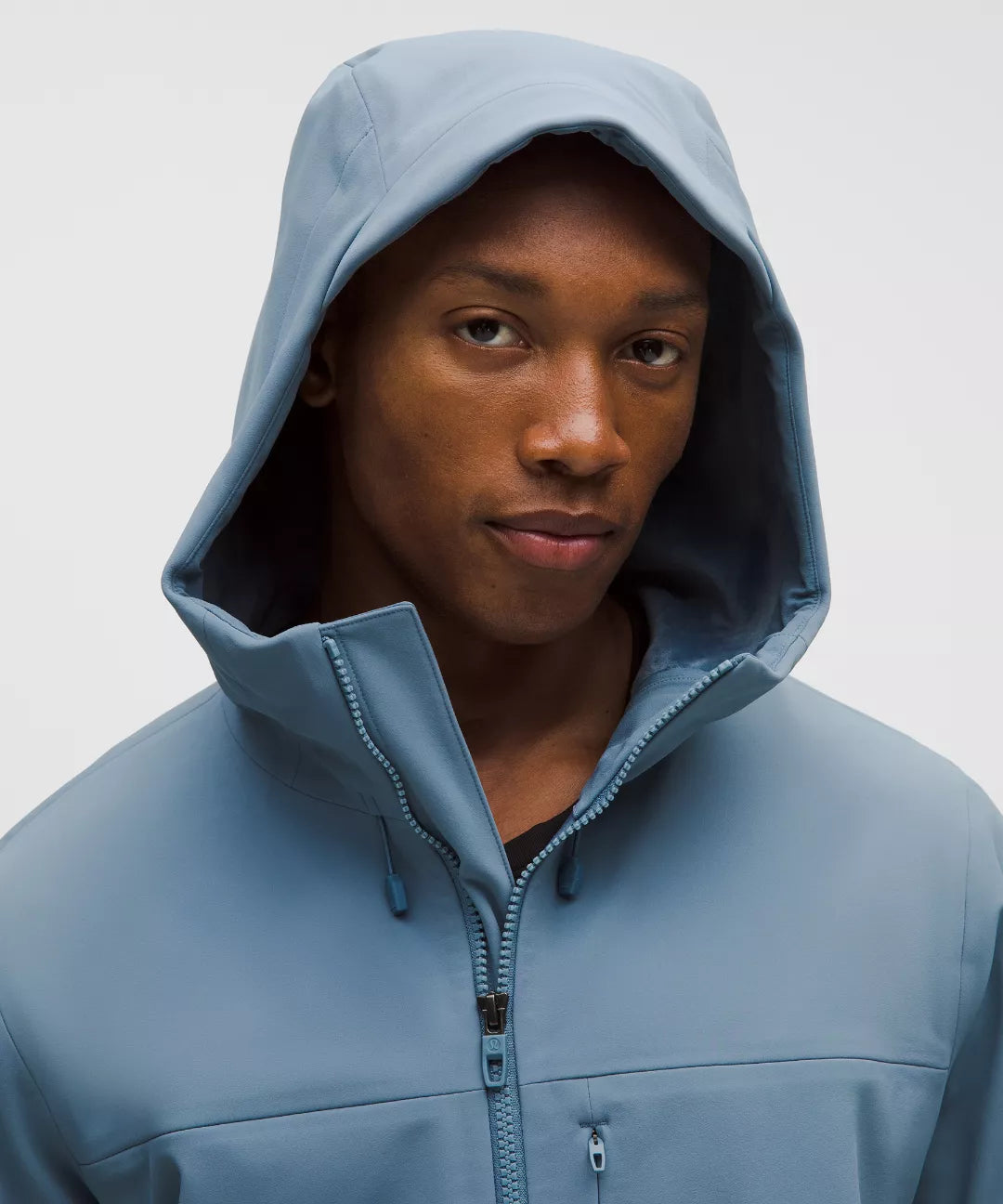 Person wearing a blue hooded jacket against a plain background