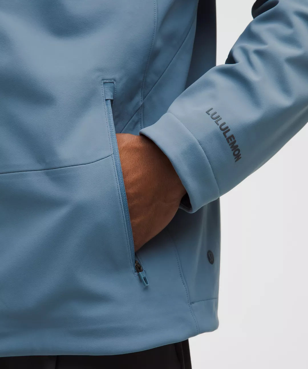 Close-up of a blue jacket with a hand in the pocket, featuring the Lululemon brand.