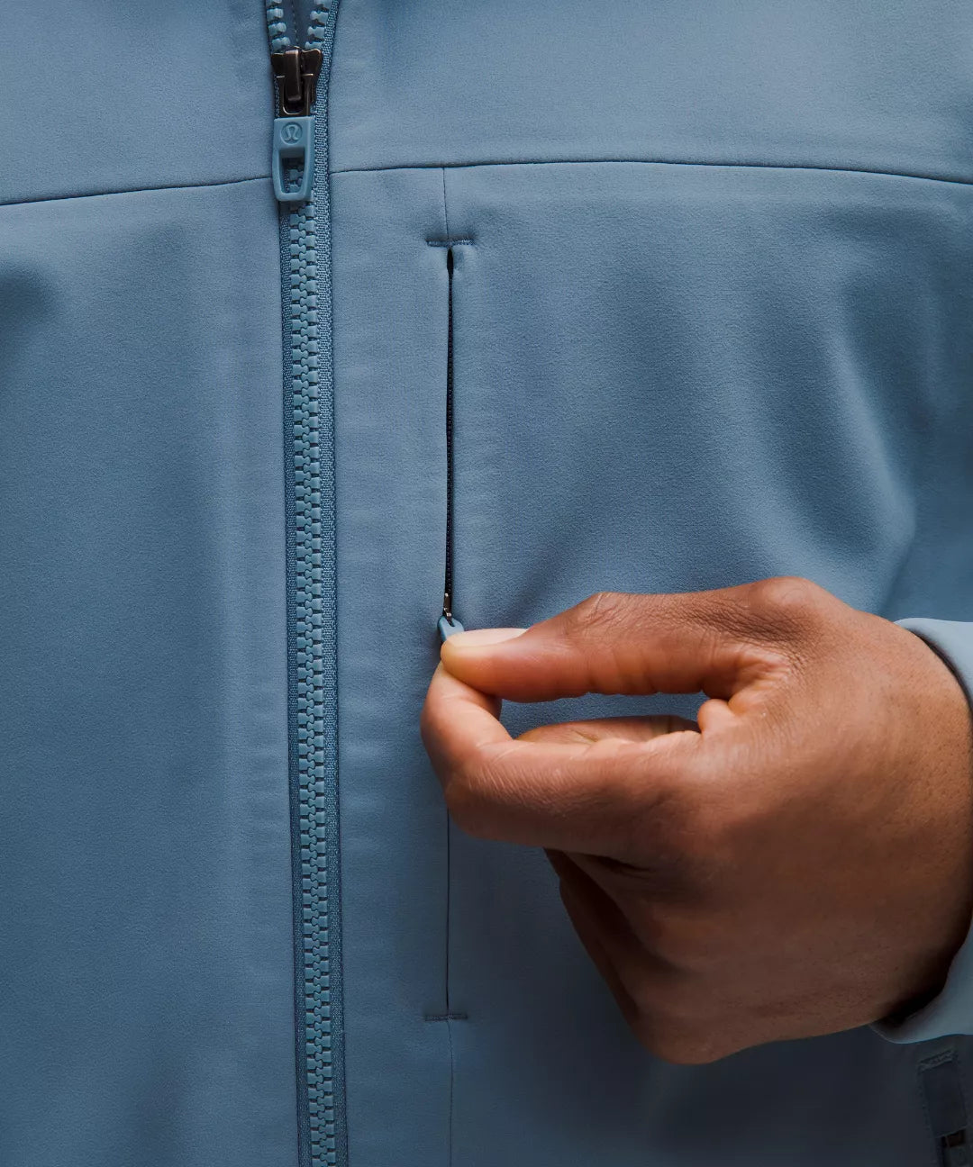 Hand zipping a blue jacket