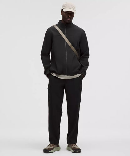 Person wearing a black jacket and pants with a beige cap on a white background
