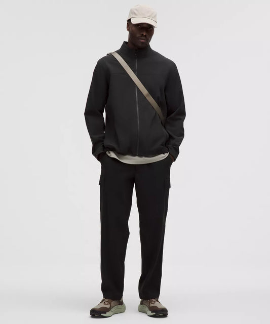Person wearing a black jacket and pants with a beige cap on a white background