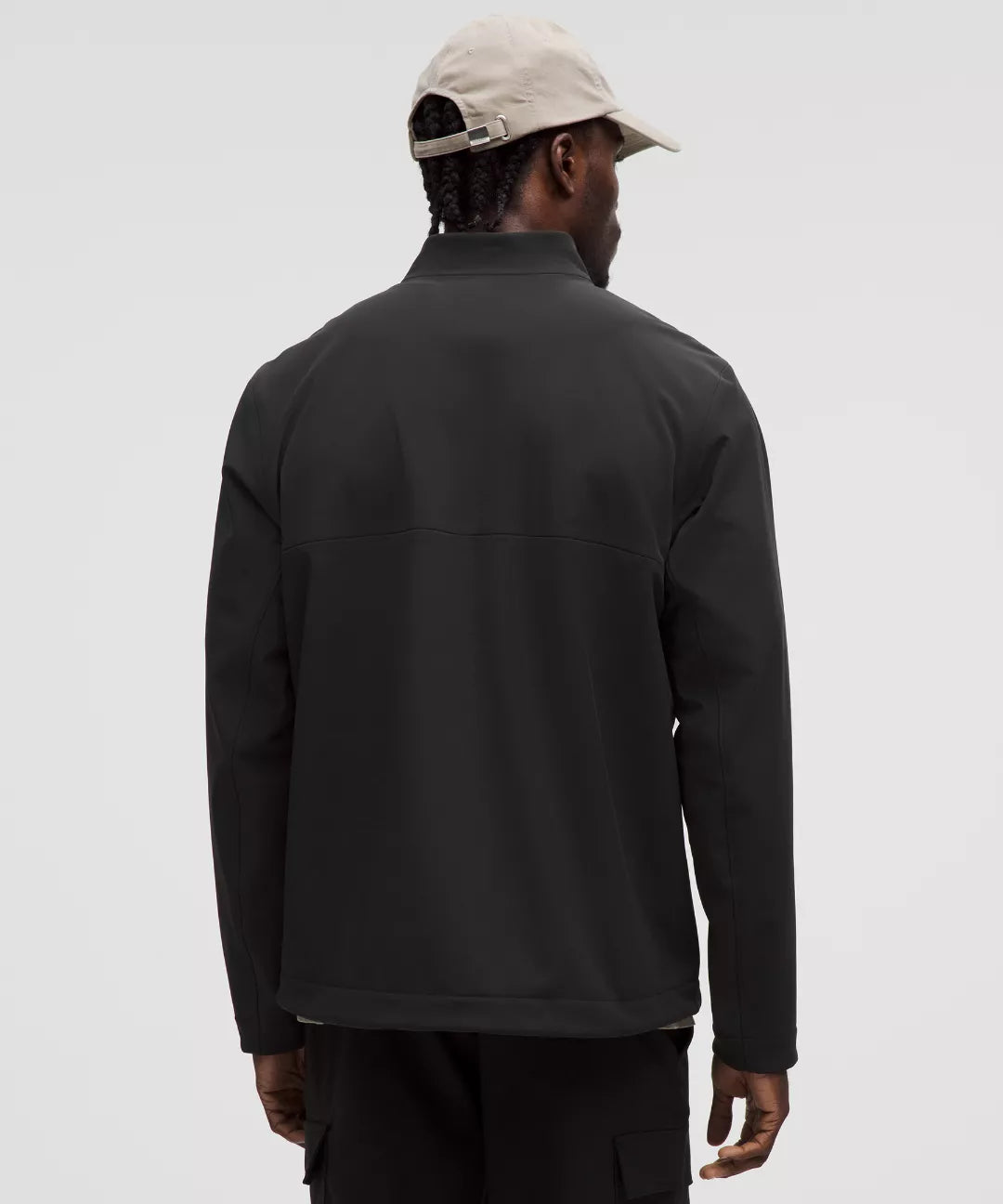 Person wearing a black jacket and beige cap on a light gray background