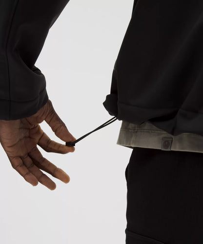 Person wearing a black jacket with a visible zipper on a light gray background