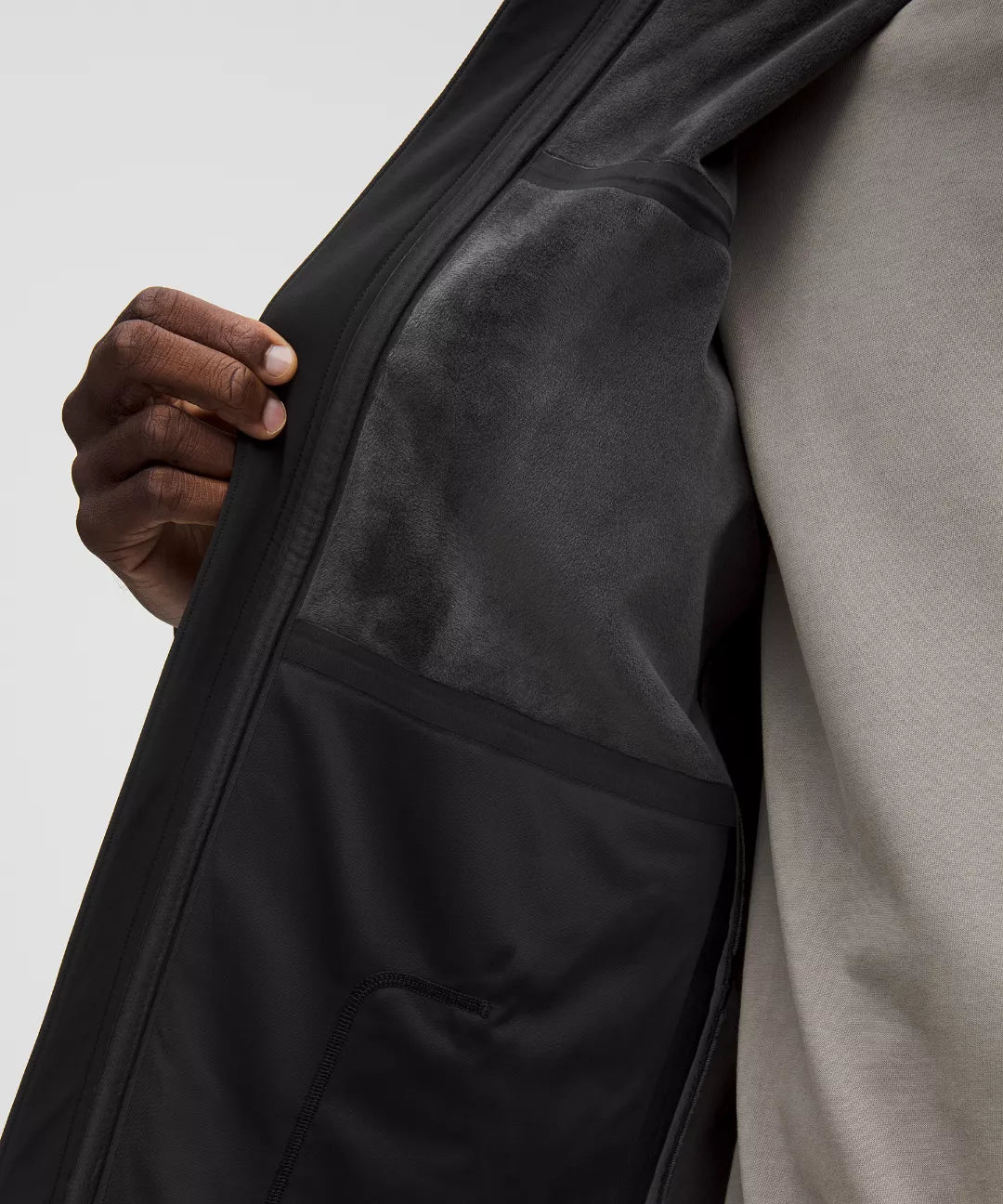 Close-up of a person wearing a black jacket with a neutral background