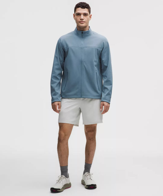 Man wearing a blue jacket and white shorts on a light gray background