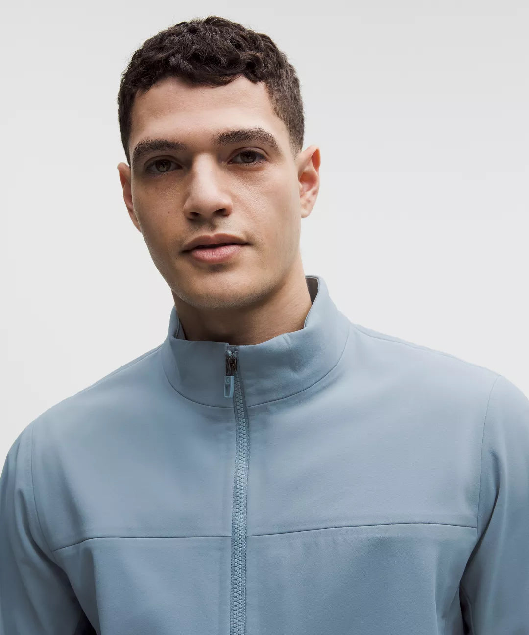 Man wearing a light blue jacket against a plain background