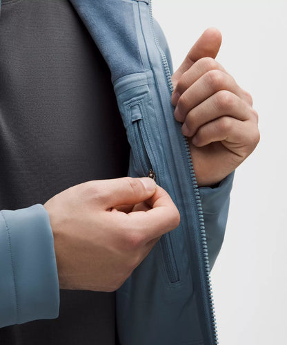 Person zipping up a blue jacket with a neutral background
