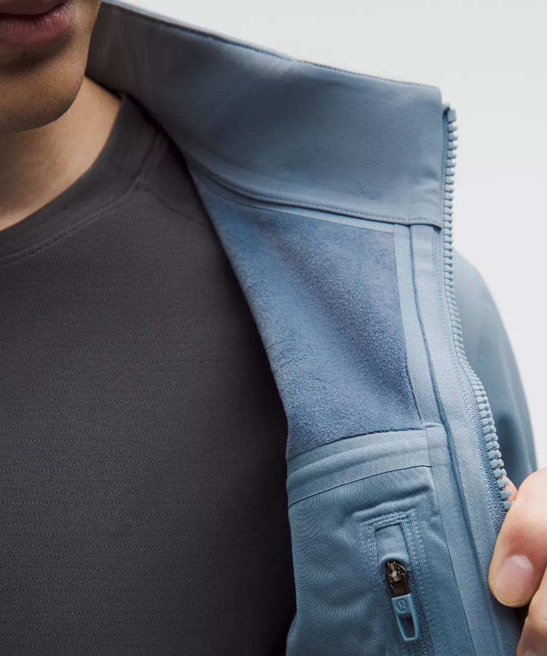 Close-up of a person wearing a light blue jacket with a zipper, focusing on the jacket's texture and design.