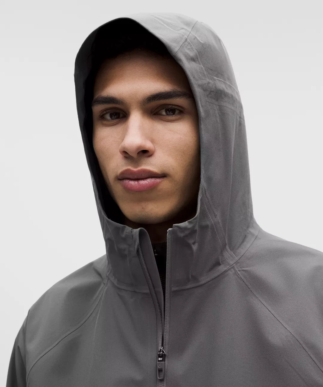 Person wearing a gray hooded jacket against a white background
