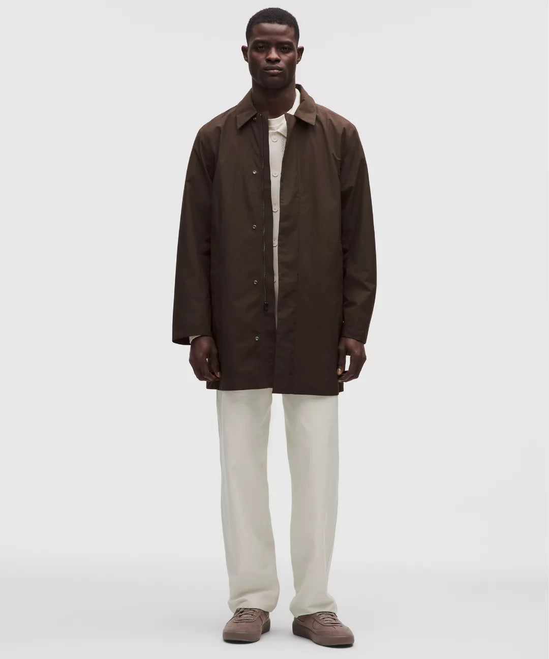 Man wearing a brown coat over a white shirt on a white background