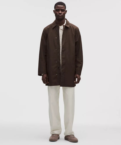Man wearing a brown coat over a white shirt on a white background