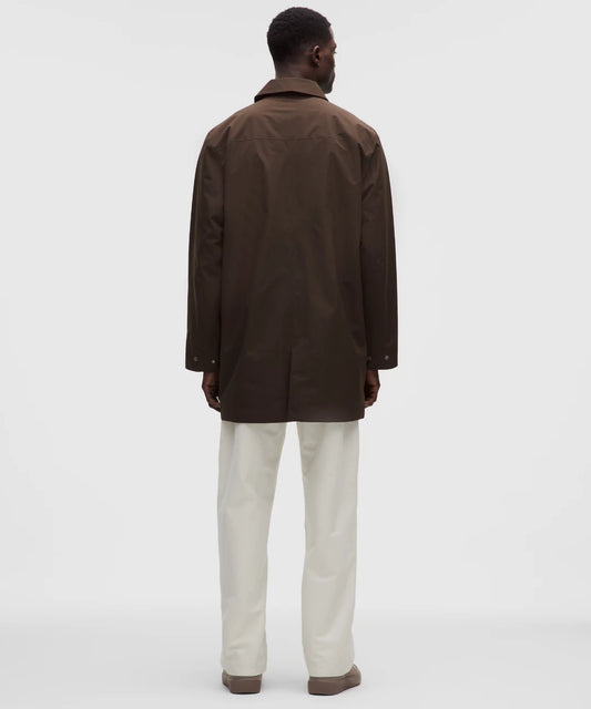 Person wearing a brown coat and white pants on a white background