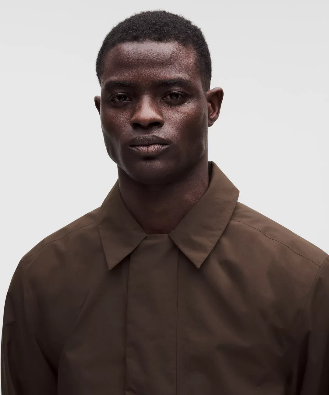 Man wearing a brown shirt against a plain background