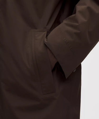 Close-up of a brown coat with a visible brand logo on a white background