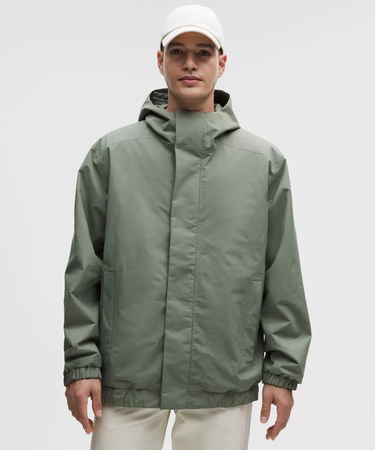 Person wearing a green raincoat and white cap on a gray background