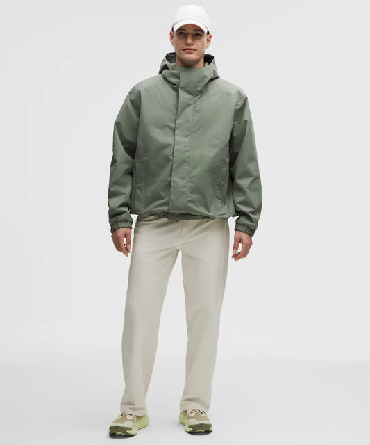 Man wearing a green raincoat and beige pants on a white background