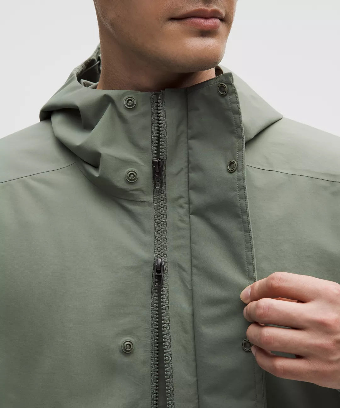 Close-up of a person wearing a green raincoat with a hood.