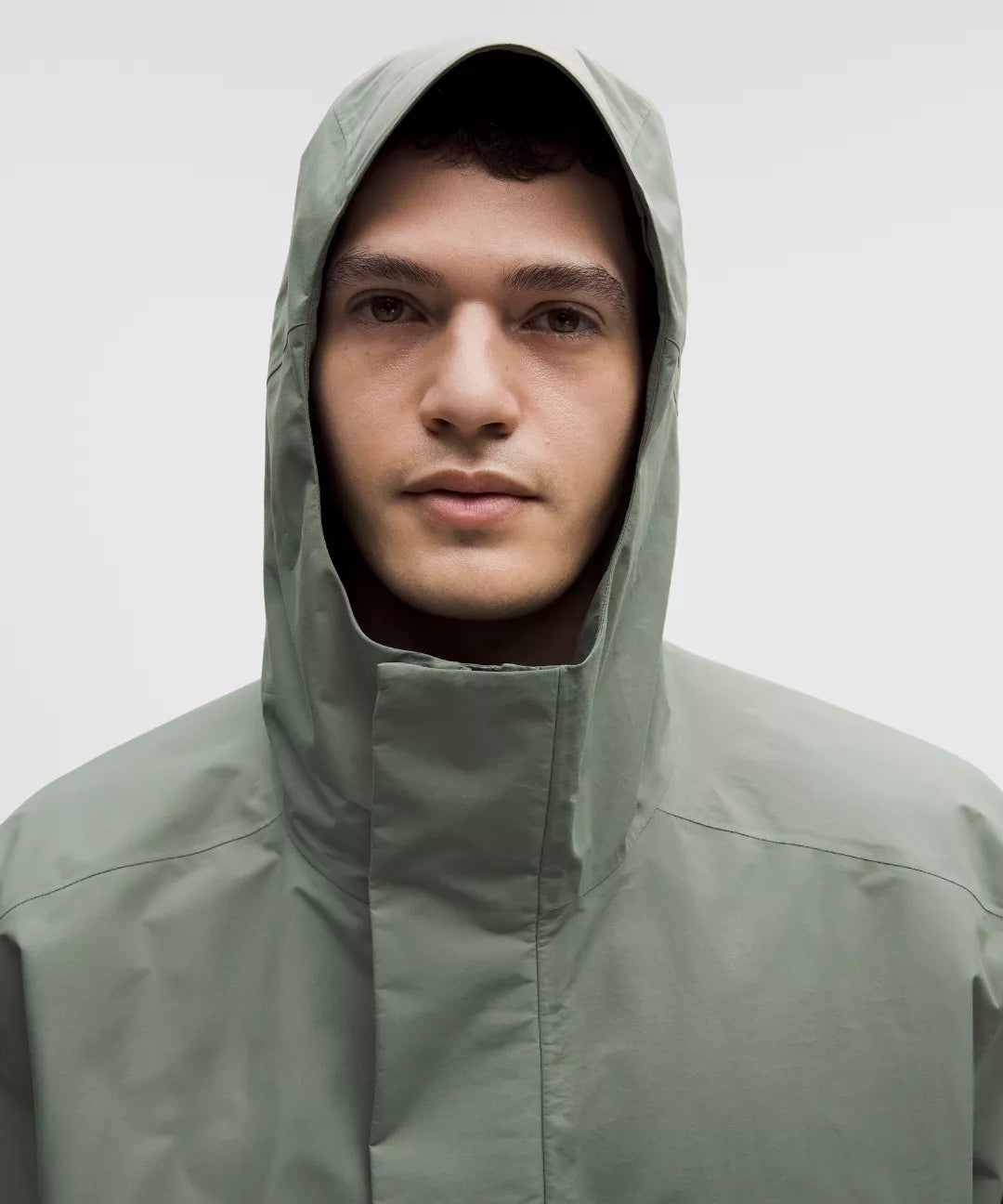 Person wearing a green raincoat with a hood against a white background