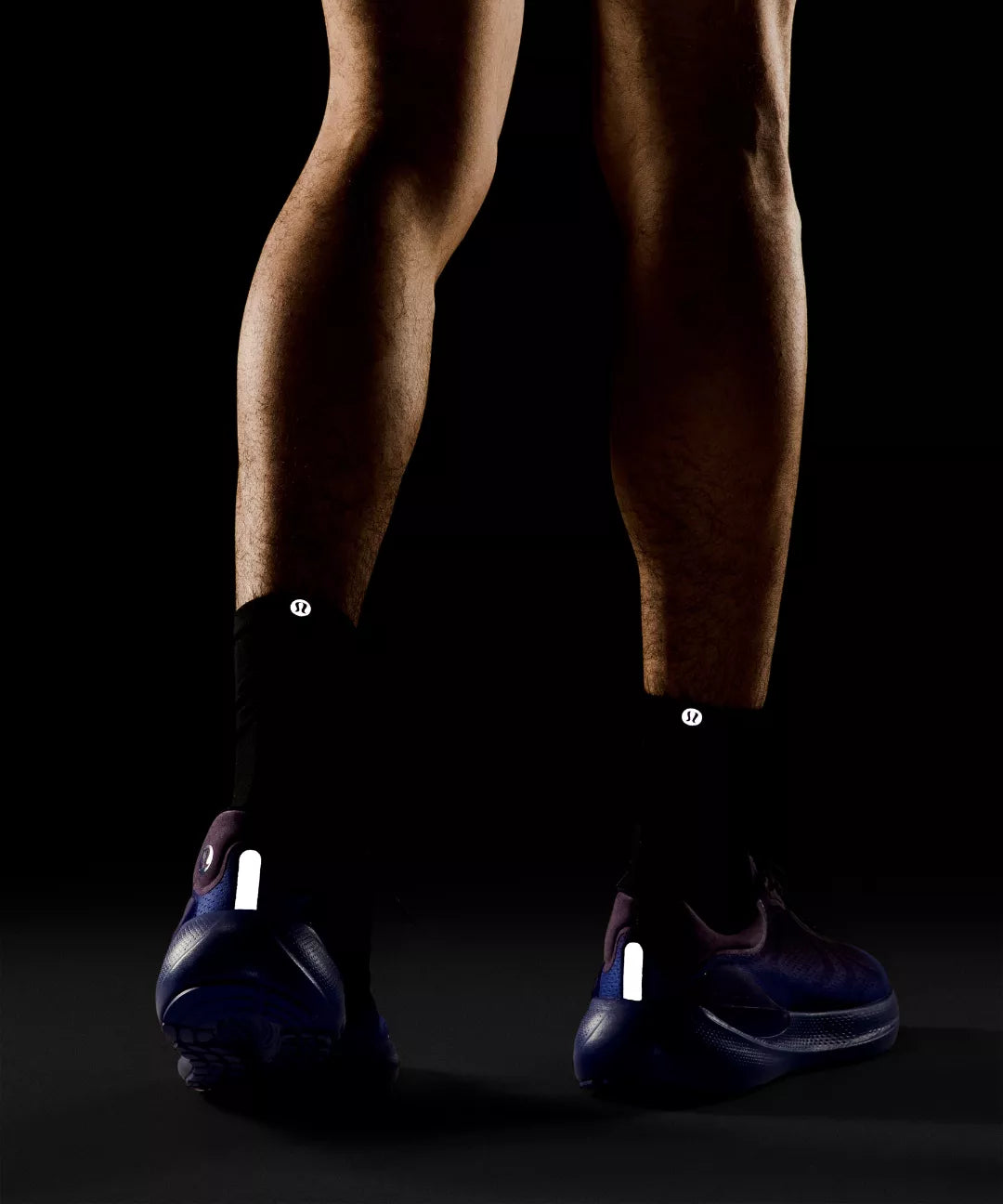 Person wearing black shoes with reflective labels on a dark background