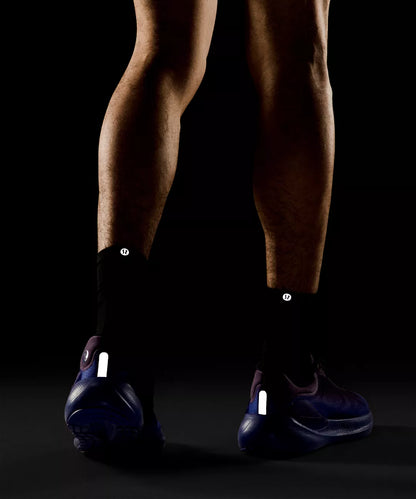 Person wearing black shoes with reflective labels on a dark background